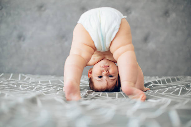 Baby standing upside down on a bed, attempting to stand or crawl